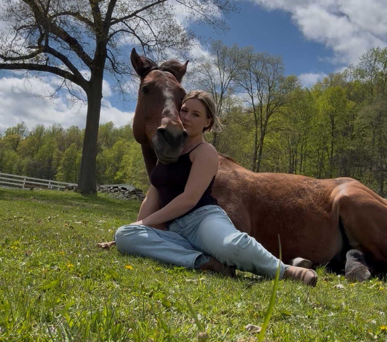 Instructor sitting on the grass beside her horse